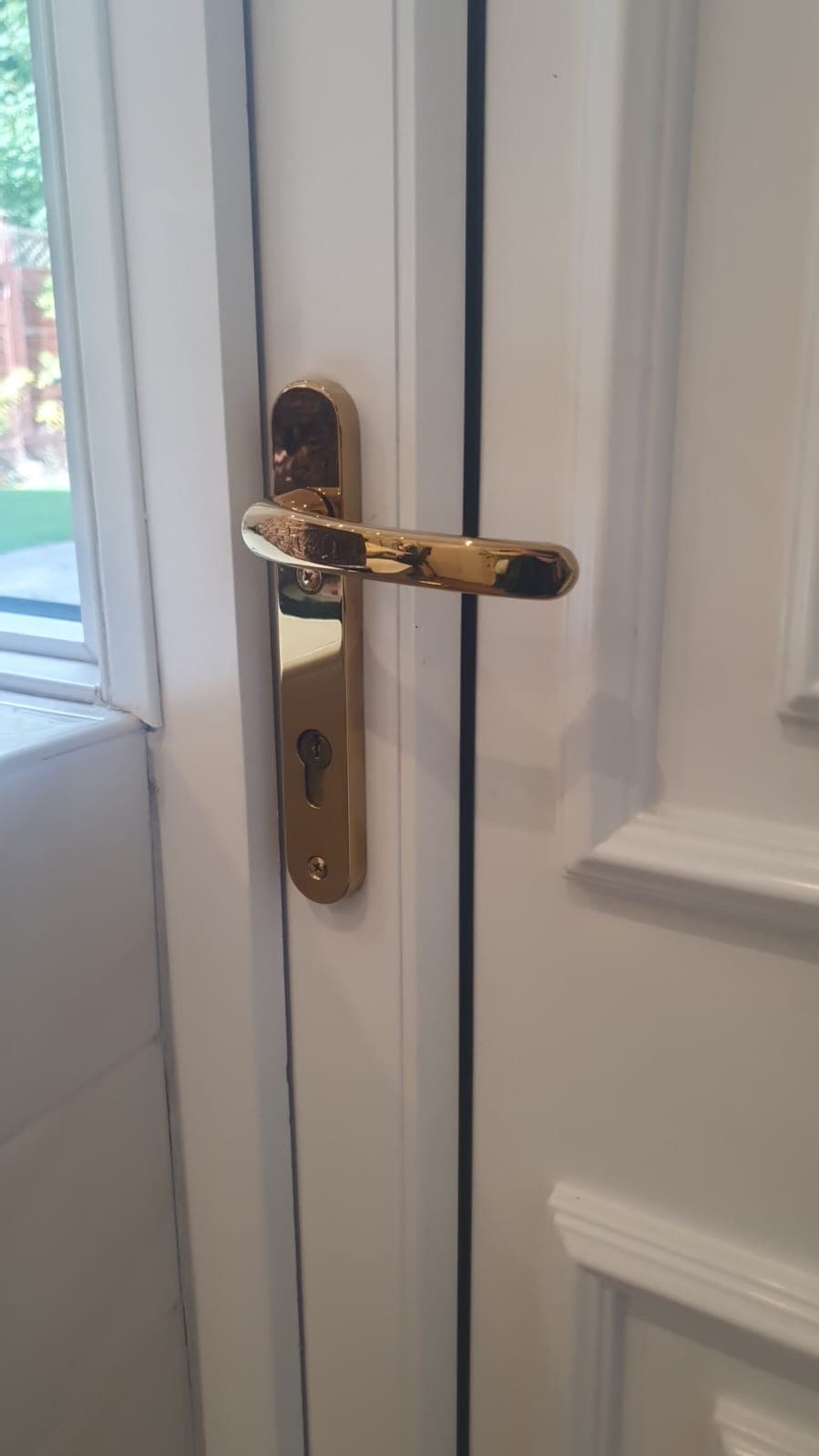 Gold lever handle and euro cylinder fitted to a white uPVC door