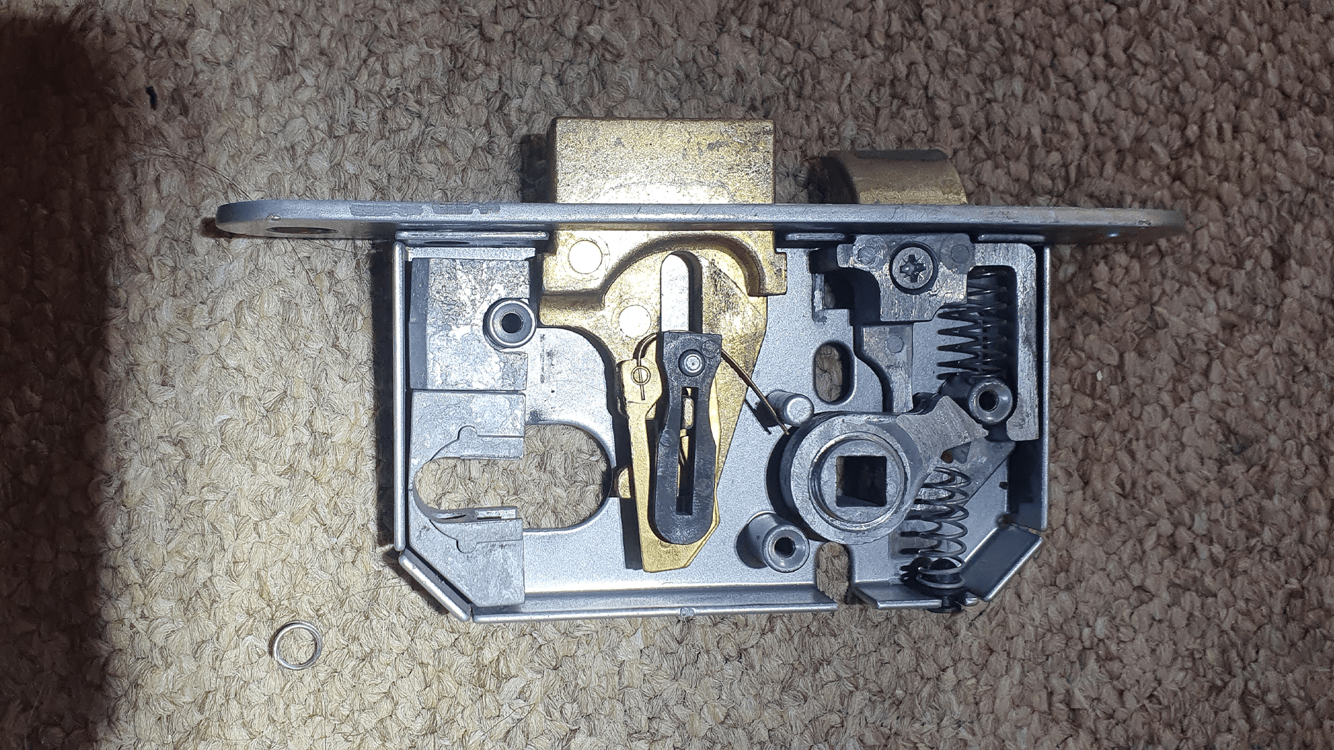 An opened mortice lock case showing the bolt and lever mechanism inside